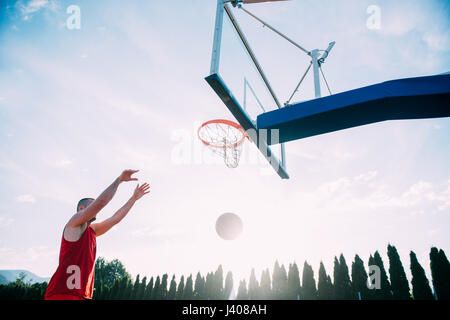 Giovane uomo di salto e facendo un fantastico Slam Dunk giocando stree Foto Stock