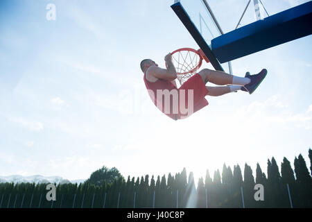 Giovane uomo di salto e facendo un fantastico Slam Dunk giocando stree Foto Stock