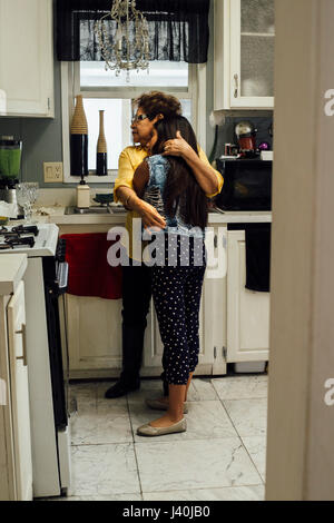 Nonna abbracciando la nipote in cucina Foto Stock