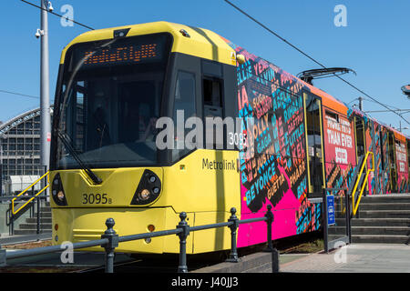 Tram Metrolink con pubblicità la copertura in vinile al Deansgate-Castlefield fermata del tram, Manchester, Inghilterra, Regno Unito Foto Stock