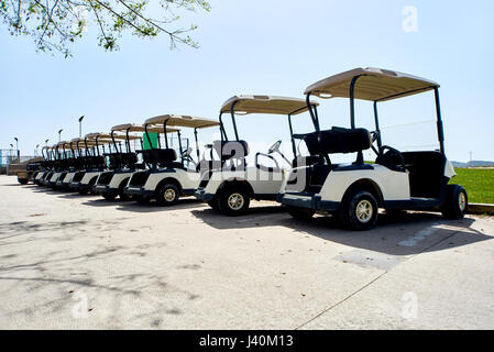 Golf car o carrelli da golf in una fila all'aperto su una soleggiata giornata di primavera Foto Stock