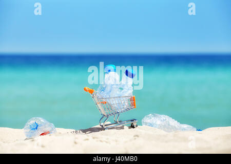 Miniatura carrello con le bottiglie di plastica vuote lasciati dai turisti su una spiaggia tropicale, inquinamento ambientale concetto foto, messa a fuoco selettiva. Foto Stock