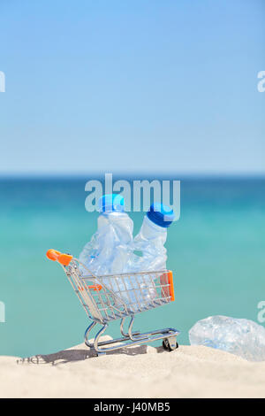 Chiudere l immagine di una miniatura del carrello con le bottiglie di plastica vuote lasciati dai turisti su una spiaggia, inquinamento ambientale concetto, il fuoco selettivo. Foto Stock