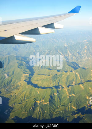 Ala di un aeroplano che vola al di sopra delle montagne. Il concetto di viaggio. Foto applicata al turismo operatori. Foto Stock