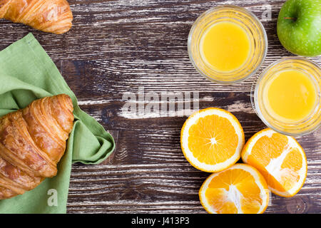 Croissant con succo d'arancia fresco su un sfondo di legno, vista dall'alto del brunch o tavolo per la colazione Foto Stock