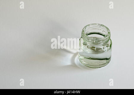 Focus-studio impilati di finestra di luce che cade su cartuccia bianco della carta attraverso il vasetto di vetro di acqua. Foto Stock