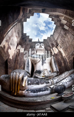Gigantesca statua di Buddha chiamata Phra Achana in Wat Si Chum al grigio cielo nuvoloso in Sukhothai Historical Park, Thailandia Foto Stock
