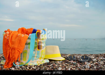 Cappello di paglia, borsa, occhiali da sole e flip flop su una spiaggia assolata Foto Stock
