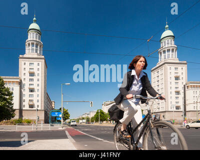 Ciclista passa di Frankfurter Tor edifici appartamento sulla storica Karl Marx Allee nella ex Berlino Est a Berlino, Germania Foto Stock