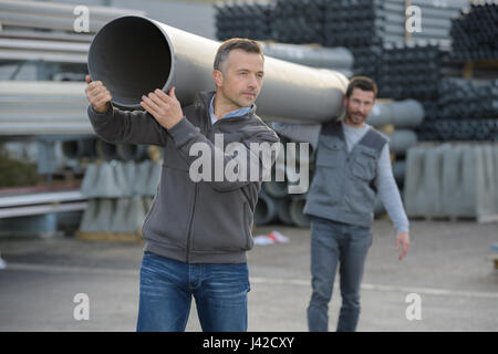I lavoratori di trasportare un tubo di acqua Foto Stock