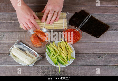 Preparazione di un rotolo di sushi al ristorante, vicino sul chef donna mani Foto Stock