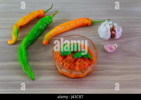 Adjika fresco pepe rosso e spezie olio nel decanter sullo sfondo della tela di sacco Foto Stock