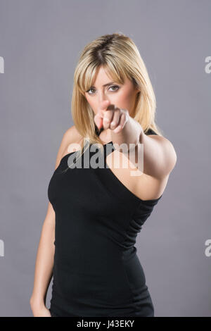 Grave giovane e bella donna bionda puntare il dito Foto Stock