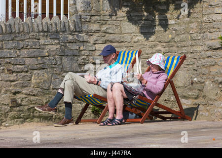 Bournemouth Dorset, Regno Unito. Il 10 maggio, 2017. Regno Unito: meteo bella calda giornata di sole come testa di visitatori al mare per rendere la maggior parte del sole a Bournemouth spiagge. Coppia senior seduti in sedie a sdraio sul lungomare guardando i giornali Credito: Carolyn Jenkins/Alamy Live News Foto Stock