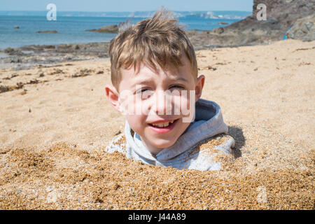 Sette anni di vecchio ragazzo giocando nella sabbia a Hope Cove, Devon, Inghilterra, Regno Unito. Foto Stock