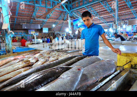 Bandar Abbas, Hormozgan Provincia, Iran - 15 aprile, 2017: un commerciante boy sorge nei pressi di un contatore con pesce fresco in un coperto Mercato del pesce. Foto Stock