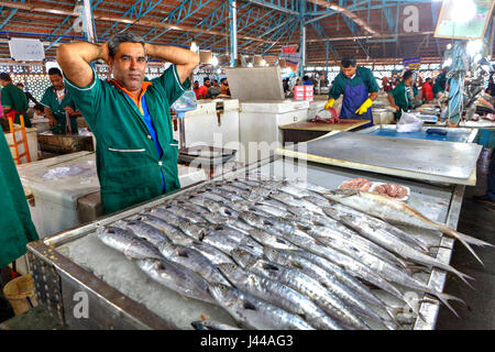 Bandar Abbas, Hormozgan Provincia, Iran - 16 aprile, 2017: un venditore di pesce in tuta verde nel mercato coperto del pesce. Foto Stock