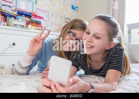 Due ragazze in posa per Selfie In camera da letto Foto Stock