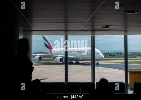 Emirates Airbus A380 che arrivano all'aeroporto di Manchester visto attraverso la finestra lounge Foto Stock