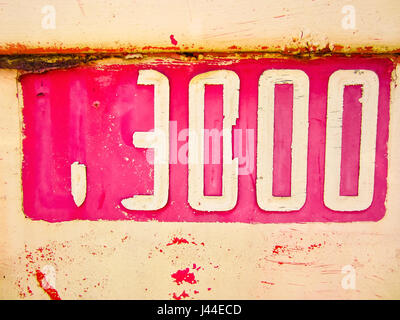 Numero metallico 3000 dipinte di giallo su sfondo rosa. Foto Stock