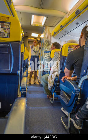 Air hostess di volo Ryanair facendo safelty dimostrazione come passeggeri watch Foto Stock