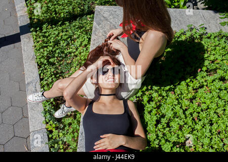 Una giovane donna che gioca con i suoi amici capelli Foto Stock