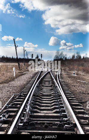 Biforcazione ferroviarie nel nord-ovest della Russia in primavera. Il cielo blu con nuvole bianche. Una fredda giornata di vento. Foto Stock