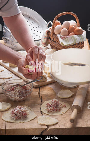 Mani femminili con belle manicure pelmeni stampo su un table-top da una quercia Foto Stock