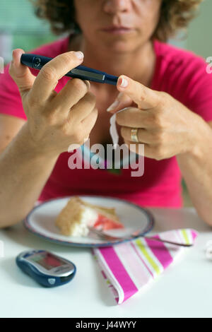 In prossimità di una donna utilizzando lancelet sul dito per prendere il campione di zucchero nel sangue. Foto Stock