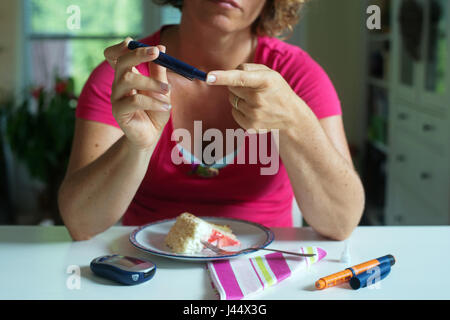 In prossimità di una donna utilizzando lancelet sul dito per prendere il campione di zucchero nel sangue. Foto Stock