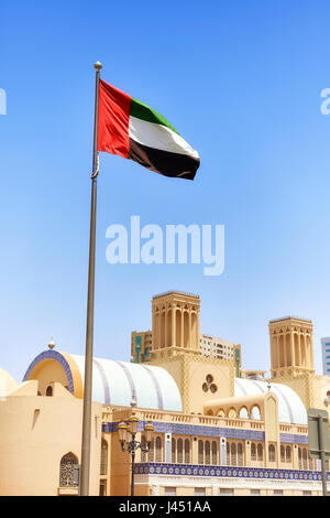 Bandiera degli Emirati Arabi Uniti contro il cielo blu in Sharjah, il fuoco selettivo, Emirati Arabi Uniti. Foto Stock