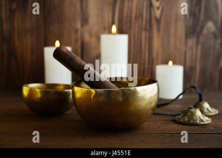 Il Tibetano handcrafted SINGING BOWLS con bastoni sullo sfondo di legno Foto Stock