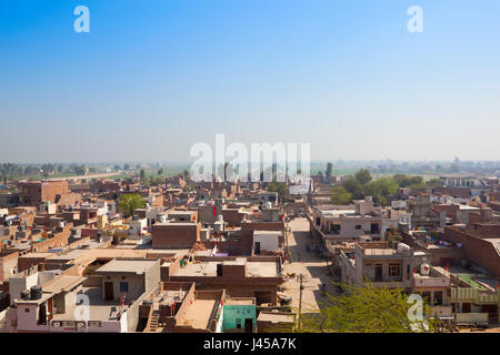 La vita quotidiana in città hanumangarh con houes e negozi e una vista della campagna lontani da bhatner fort in Rajasthan in India sotto un cielo blu Foto Stock