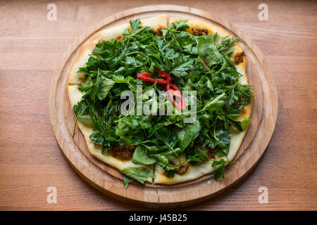 Armeno sottile pane pita con il formaggio e il pepe e le erbe per il backup. Lamadjo su una piastra. Close up. vista superiore Foto Stock