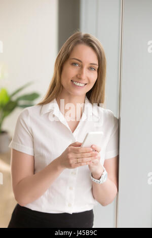 Donna in piedi con lo smartphone alla moda in mani Foto Stock