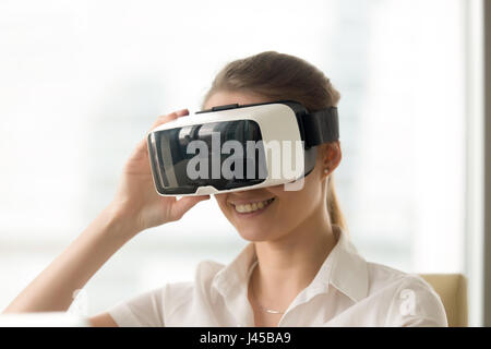 Donna sorridente cercando in occhiali per realtà virtuale Foto Stock