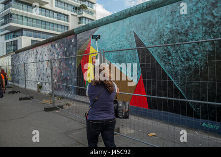 I turisti scattare foto di una sezione della East Side Gallery su Mühlenstrasse, Berlino, sito di pochi ultimi rimanenti parti del muro di Berlino ornato Foto Stock