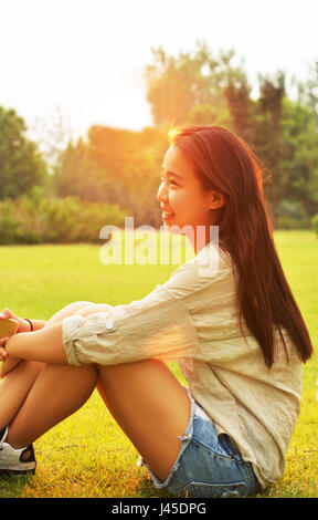 Sorridente ragazza asiatica. Nelle prime ore del mattino ritratto in controluce Foto Stock