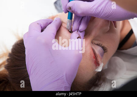 Cosmetologo applicare trucco permanente sulle sopracciglia Foto Stock