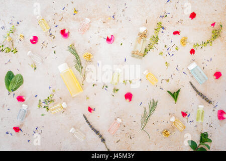Vari oli skincare, fresche erbe officinali e fiori, trattamento spa, sul cemento. Vista dall'alto, uno spazio vuoto Foto Stock