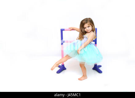 Bellissima bambina pratiche e si estende per la sua danza di routine. ella è vestito in un costume da ballerina di aqua e lilla. Foto Stock
