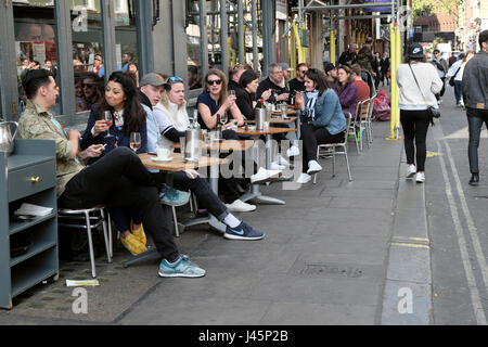 Persone che bevono vino e birra seduti ai tavoli rilassandosi all'esterno di un pub ristorante in primavera su una strada a Soho, Londra Inghilterra KATHY DEWITT Regno Unito Foto Stock