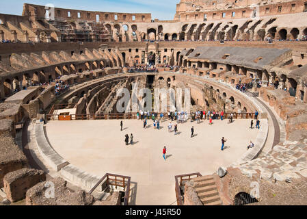 Un ampio angolo di vista interna dell'anfiteatro all'interno del Colosseo con i turisti i visitatori in una giornata di sole con cielo blu preso dal livello medio 2. Foto Stock