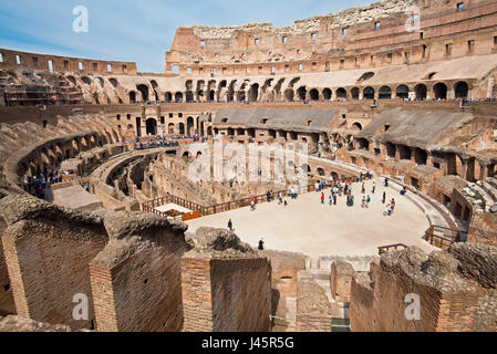 Un ampio angolo di vista interna dell'anfiteatro all'interno del Colosseo con i turisti i visitatori in una giornata di sole con cielo blu preso dal livello medio 2. Foto Stock