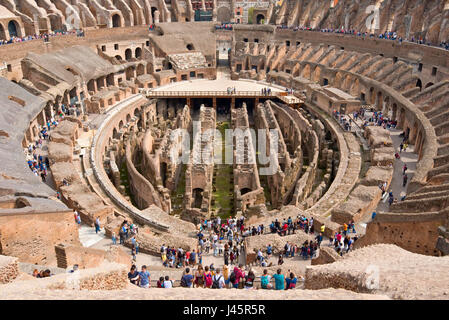 Un ampio angolo di vista interna dell'anfiteatro all'interno del Colosseo con i turisti i visitatori in una giornata di sole con cielo blu preso dal livello superiore 3. Foto Stock