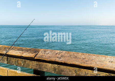 Canna da pesca su una rampa di legno con vista sull'oceano Foto Stock