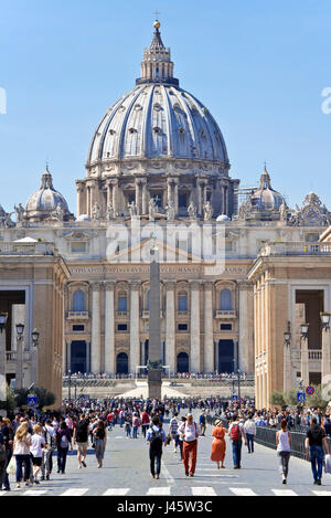 Compressi in prospettiva della Basilica di San Pietro a Roma in una giornata di sole con cielo blu e la folla di turisti in primo piano. Foto Stock