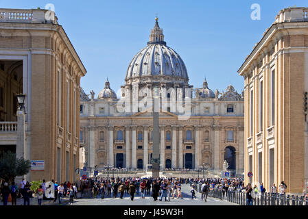 Compressi in prospettiva della Basilica di San Pietro a Roma in una giornata di sole con cielo blu e la folla di turisti in primo piano. Foto Stock