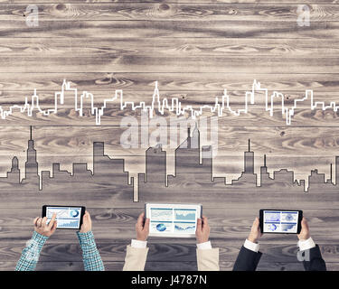 Un gruppo di tre persone con i dispositivi in mani lavorando insieme come simbolo del collegamento in rete e comunicazione Foto Stock