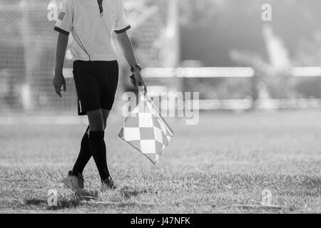 Arbitro assistente in movimento lungo il diversivo durante una partita di calcio. Arbitro assistente permanente al marginale. Foto Stock